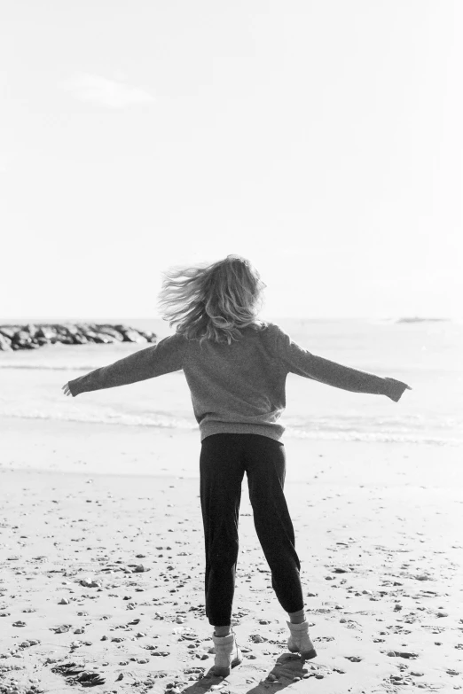 a woman in an all black outfit stands on the beach looking at the water