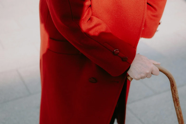 an older woman in a red coat is holding an umbrella