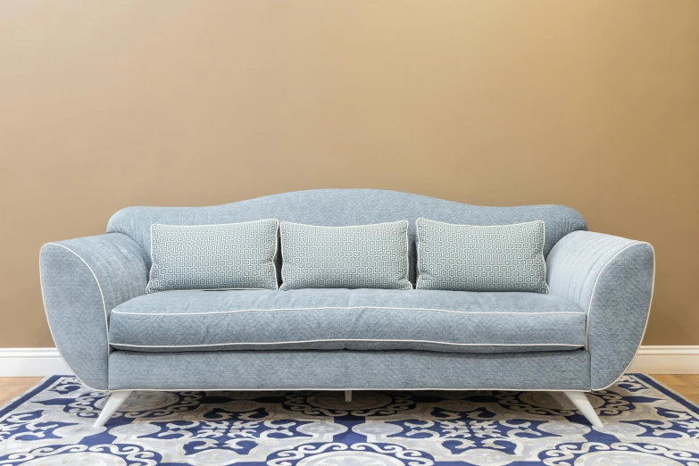 a light blue sofa with decorative pillows in front of a beige wall