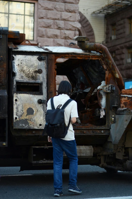 a person standing by a burnt out truck