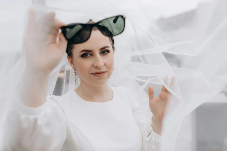 woman in white dress and dark glasses wearing veil