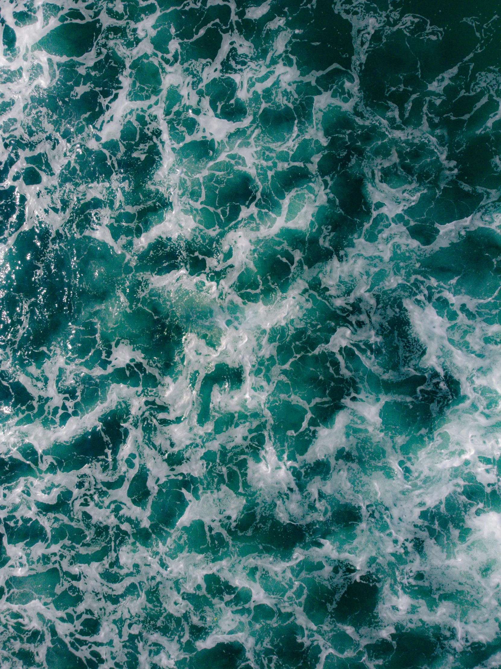 an aerial view of some water with a blue sky in the background