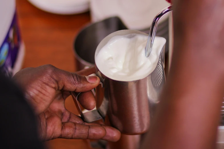 a person with a spoon pouring milk into a cup