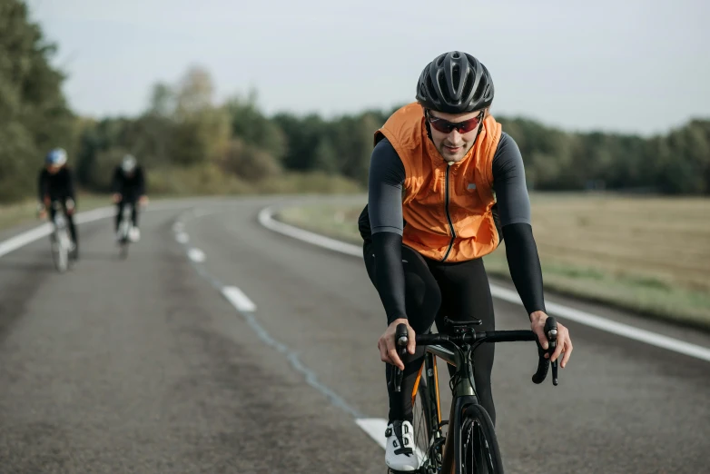 three men racing bikes down the road together