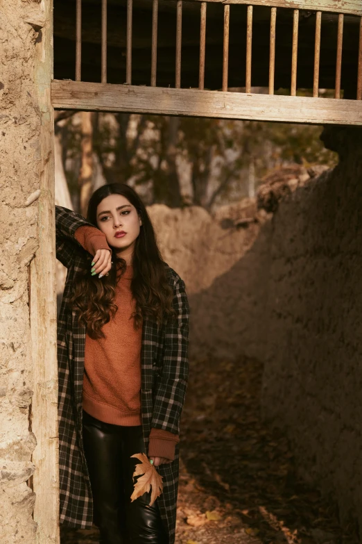 a woman poses near a building with a fall tree