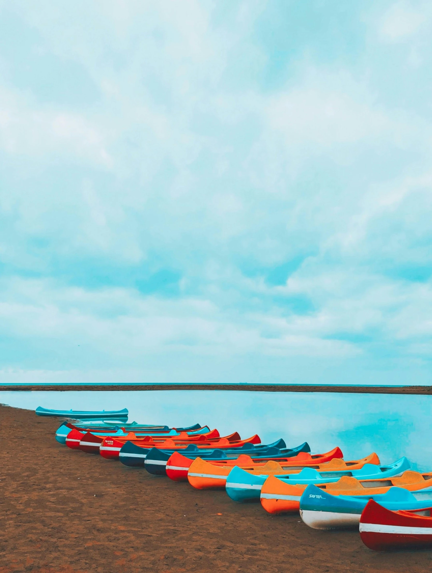 an assortment of canoes sit on the edge of the water