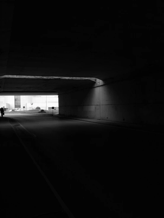 black and white image of a person standing alone in a tunnel