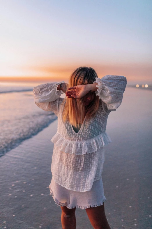 the blonde woman wearing a dress is walking along the beach