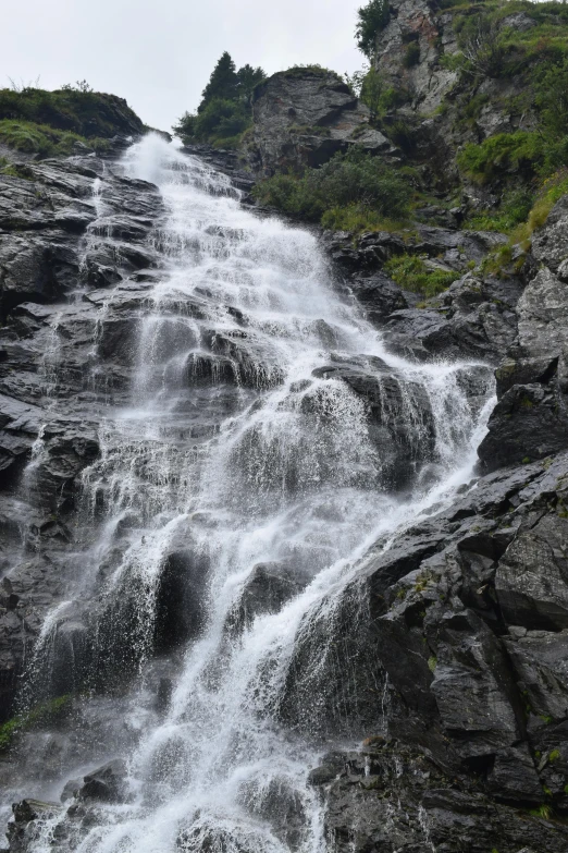 a long waterfall that is running down a mountain side