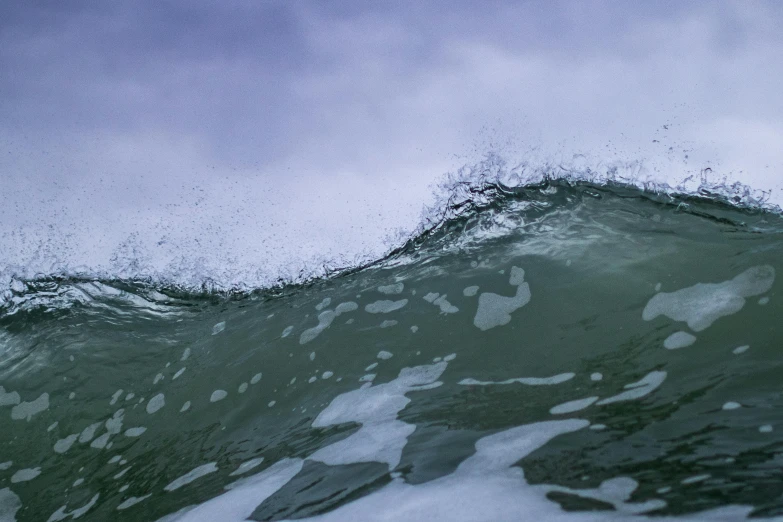 large wave crashing on shore with sky in the background