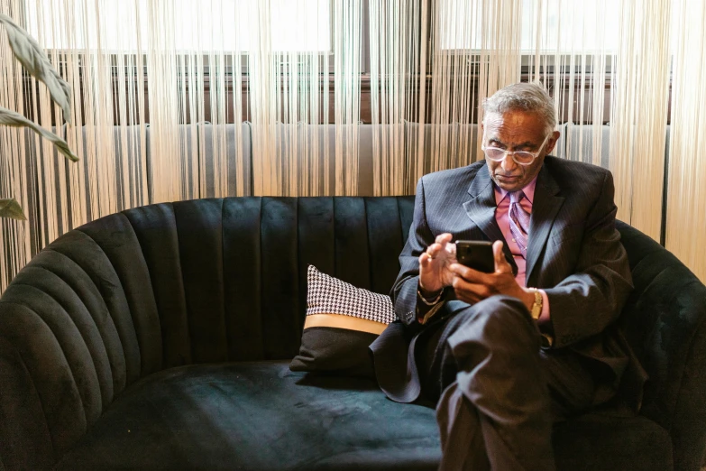 a man sitting on a black couch looking at his phone