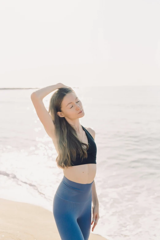 woman at beach with hands behind head and looking up