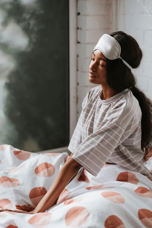 a girl in a white dress with a headband sitting on her bed