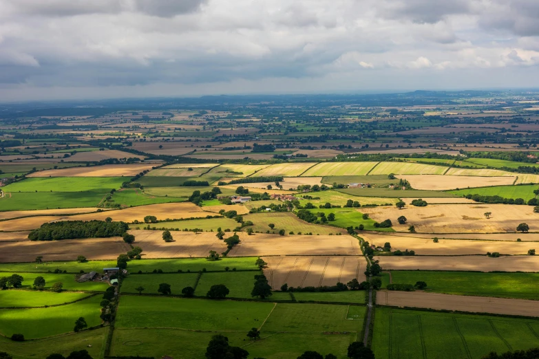 farmland with rolling green and yellow fields and clouds in the sky