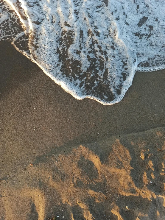 waves in the sand on a beach near the water