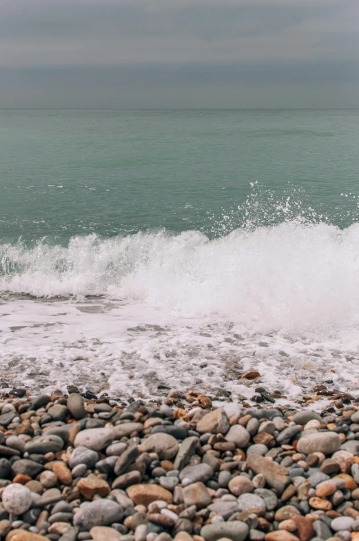 a rocky beach near the ocean with the wave crashing