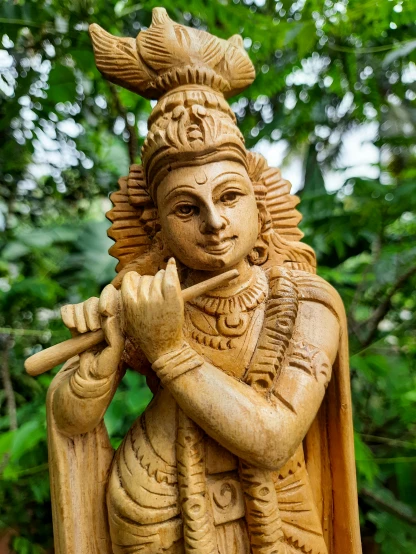 wooden statue of indian god holding musical instrument