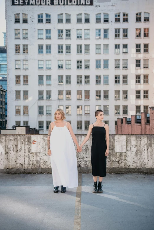 two women holding hands walking down the road in front of tall buildings