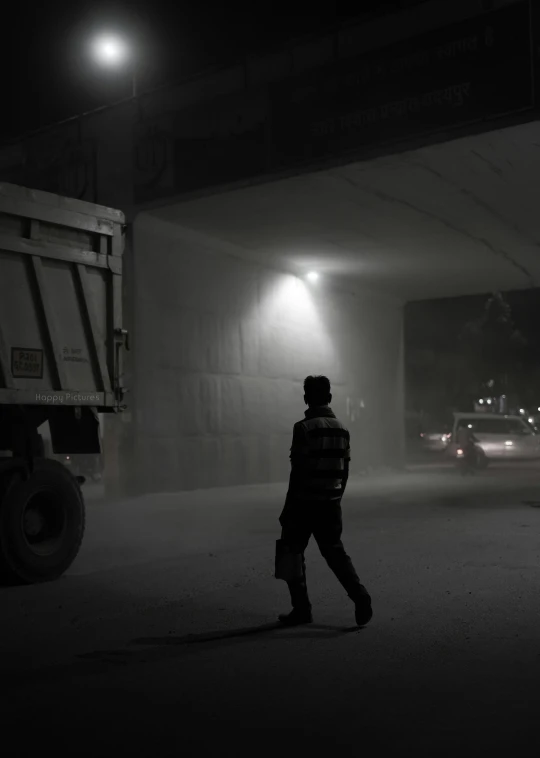 a man stands in the street at night near a dumpster