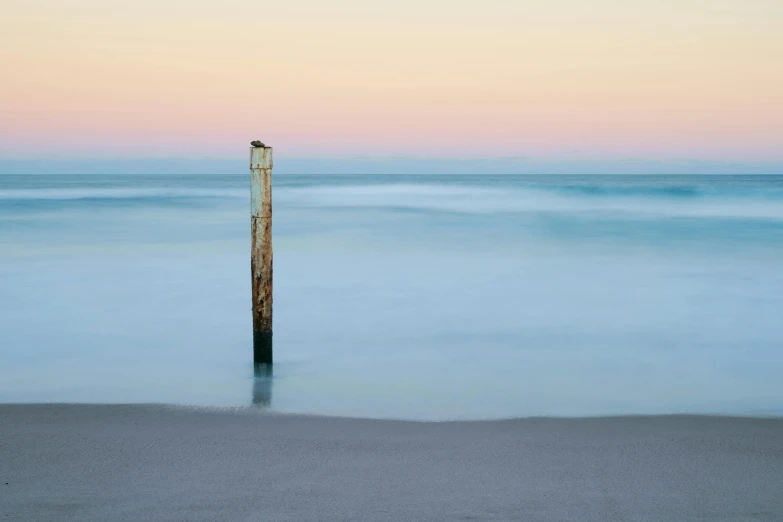 a beach view shows the water and sand as dusk colors are changing