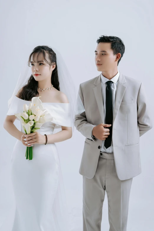an asian couple standing next to each other in wedding attire
