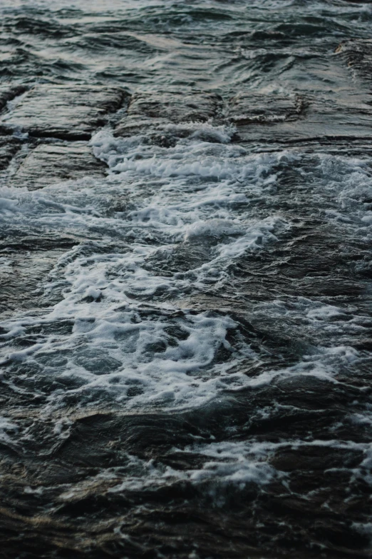 water with white foam on it is moving with the tide