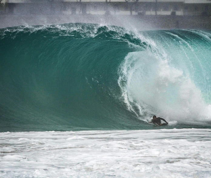 person riding the top of a large wave on a surfboard