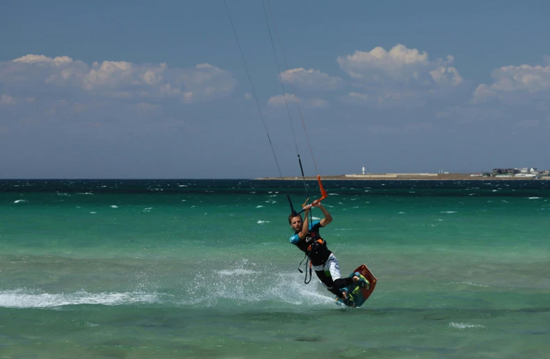 someone kiteboarding in the blue ocean, wearing all black