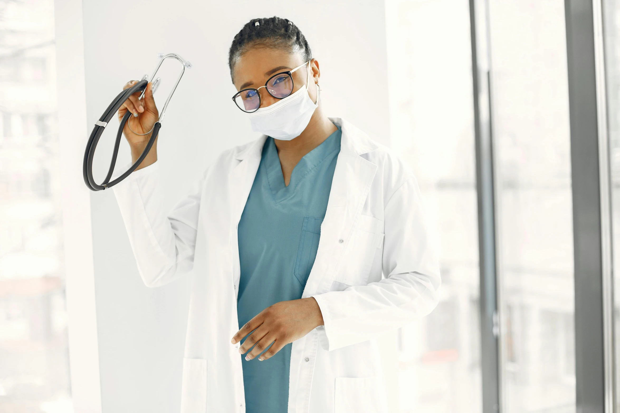 a female doctor wearing a mask holding up a pair of glasses