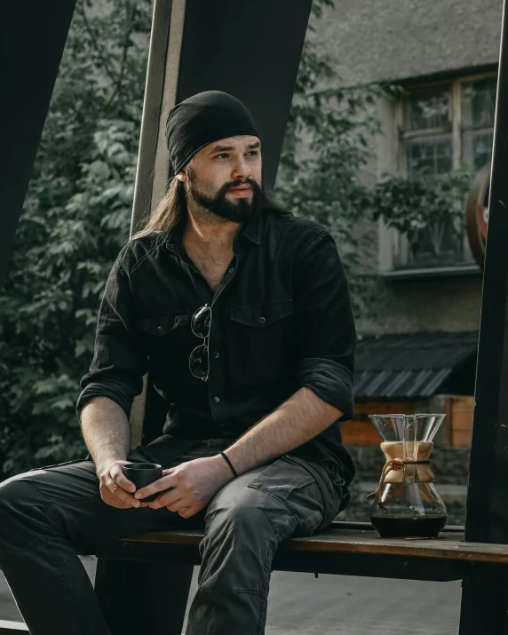 a man sitting on a wooden bench with a coffee cup