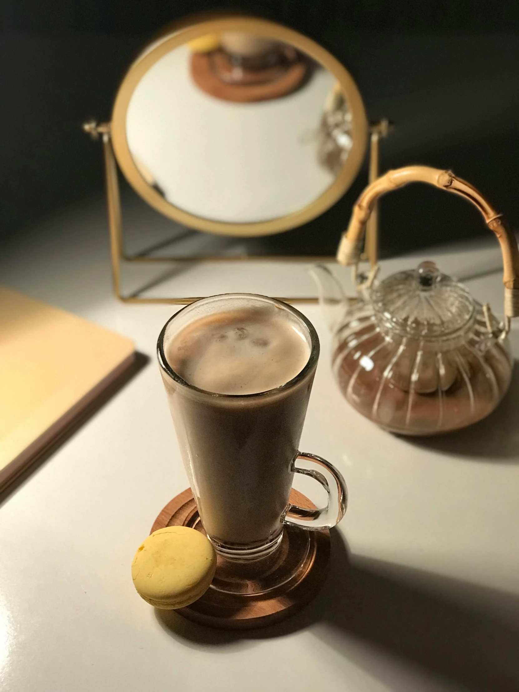 there is a cup with coffee, cookies and a mirror