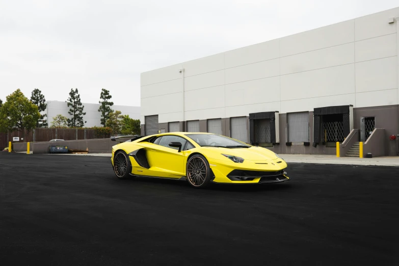 the yellow sports car is parked next to the warehouse