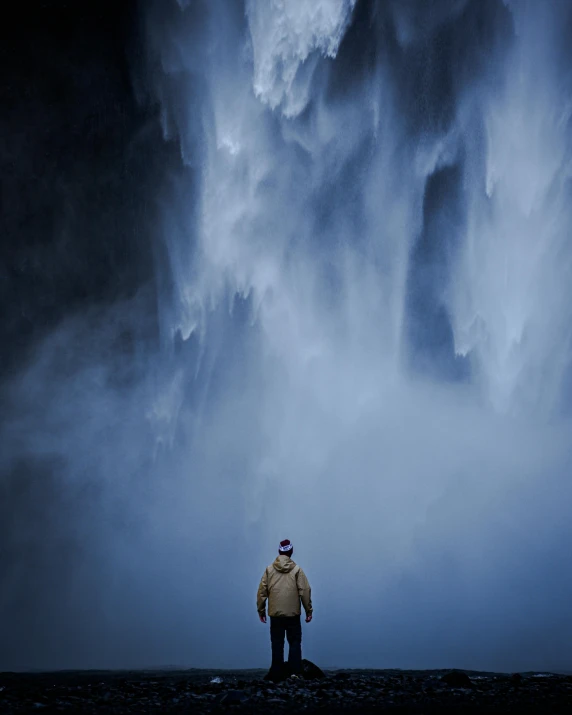 man standing under large, threatening storm clouds at night