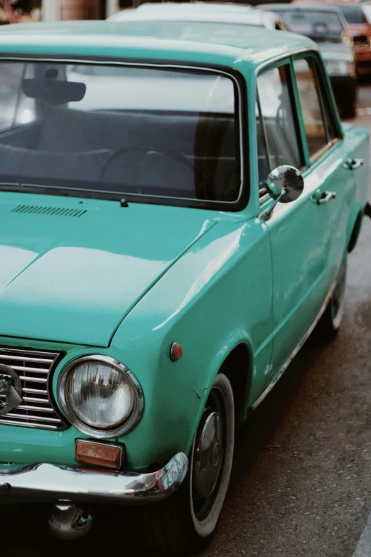 an older blue car is parked on the street