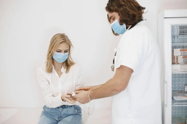 man in white shirt and protective mask checks his hand on a woman's finger