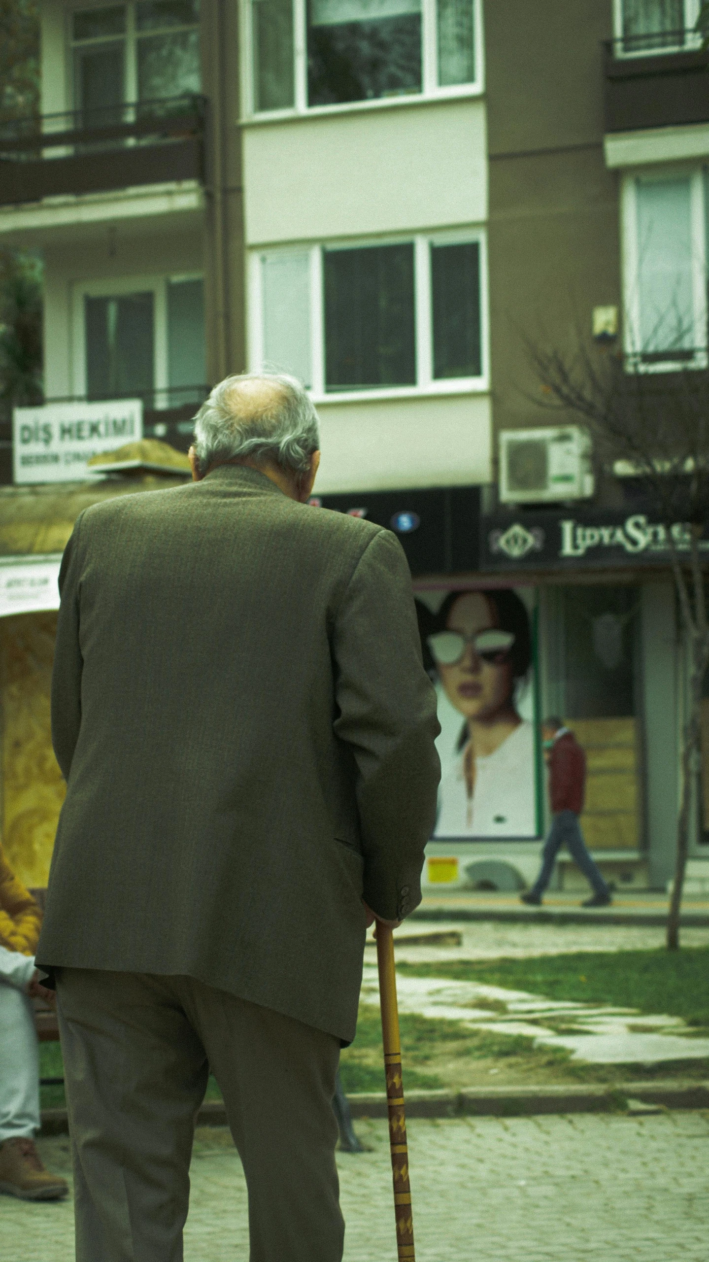 an old man walking on the street holding a cane