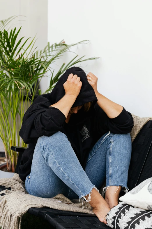 a woman sitting on a couch covering her face