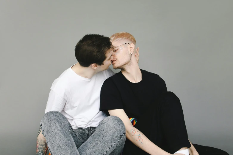 a guy in a white shirt is kissing another man