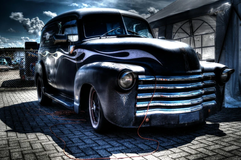 an old black truck with black accents parked near a building