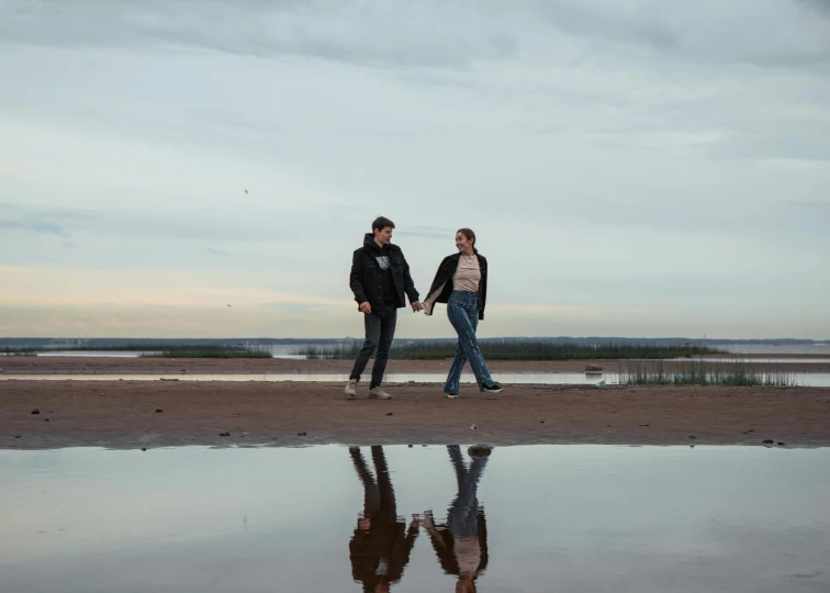 the two people are walking down the beach