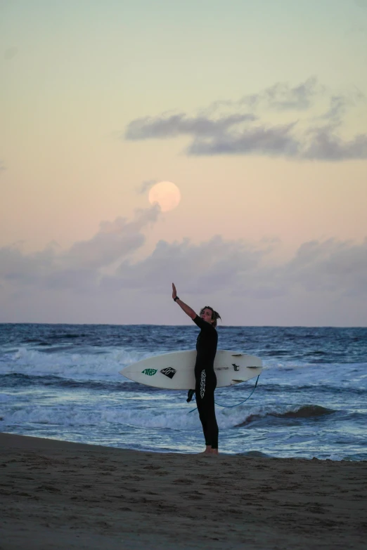 the man is standing on the beach holding his surfboard