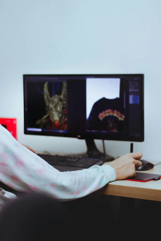 a person wearing a striped shirt is looking at two computer screens