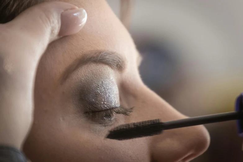 the girl is putting makeup on her eyebrows