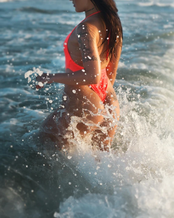 a woman in red swim suit on water next to rocks