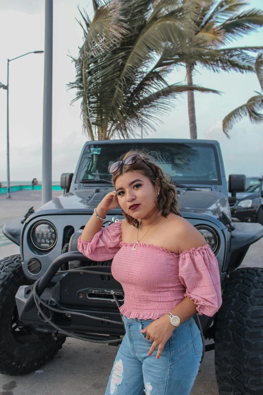 young woman posing in front of large black truck