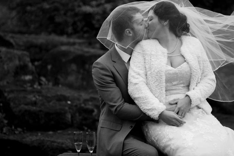 a bride and groom kissing with the veil over their head