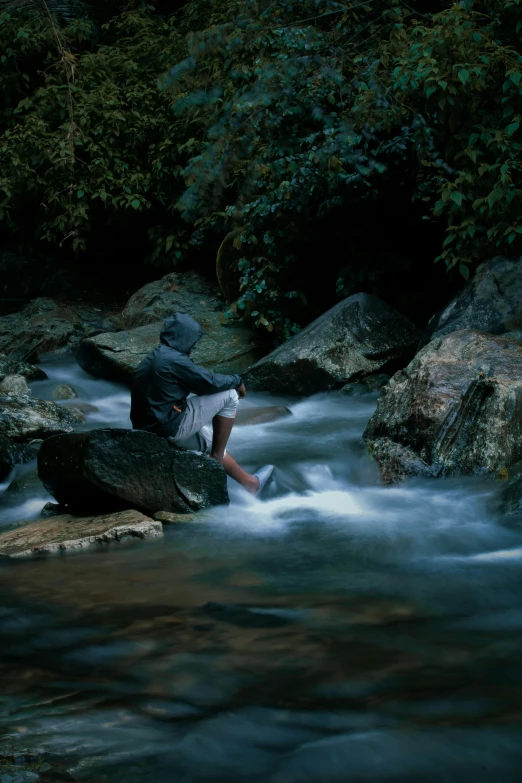 a man sitting on rocks next to water