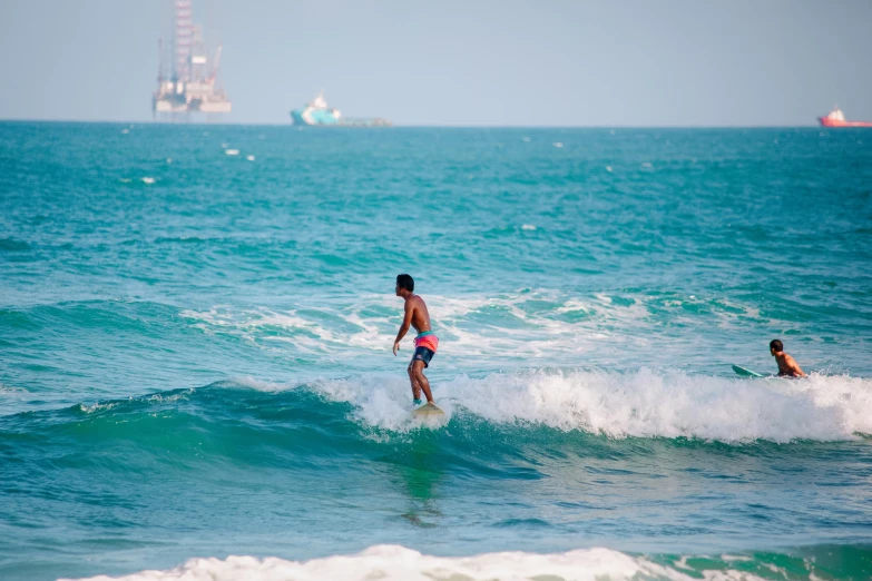 two surfers are in the water and one is walking along the beach