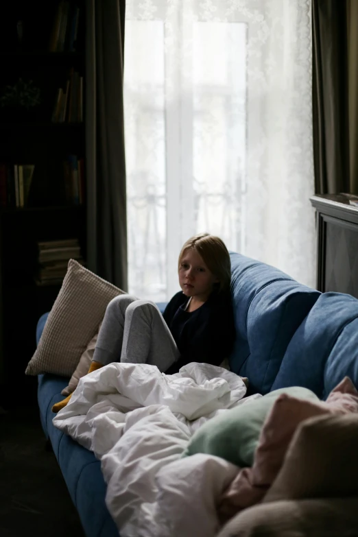 a girl lying on a couch with many white and blue sheets on it