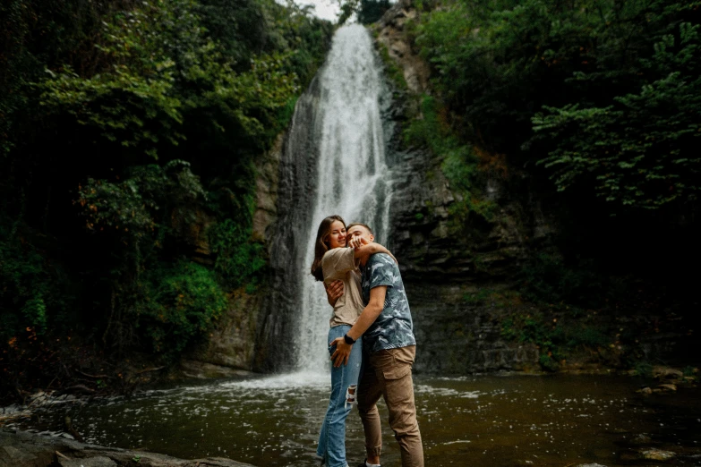 an image of a man and woman kissing near the waterfall